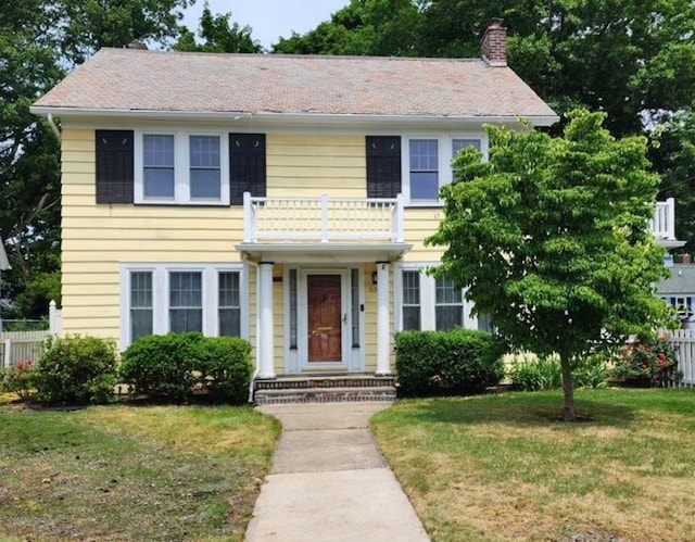 colonial house with a front lawn and a balcony