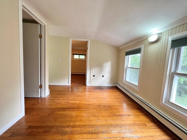 unfurnished room featuring baseboard heating, plenty of natural light, vaulted ceiling, and light hardwood / wood-style floors