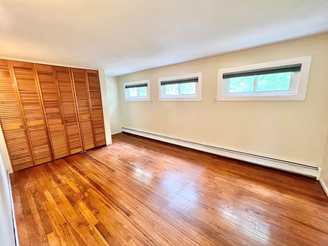 unfurnished bedroom featuring a baseboard radiator, light hardwood / wood-style floors, and a closet