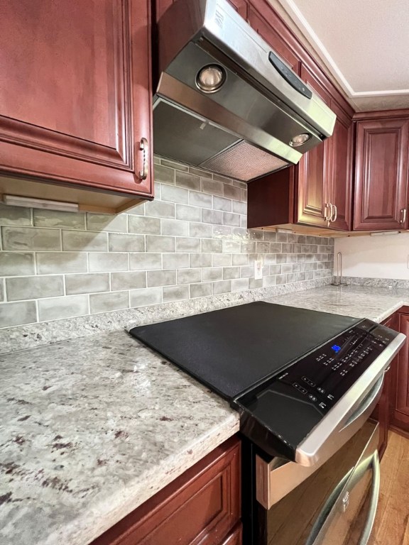 kitchen with stainless steel electric range, light hardwood / wood-style flooring, extractor fan, light stone countertops, and decorative backsplash