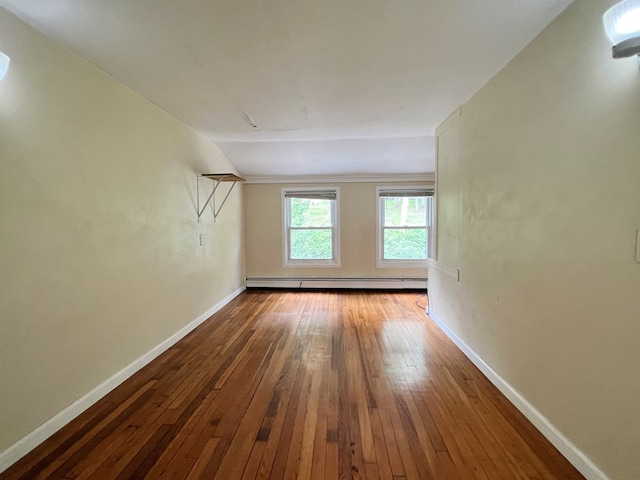 spare room with hardwood / wood-style flooring, lofted ceiling, and a baseboard heating unit