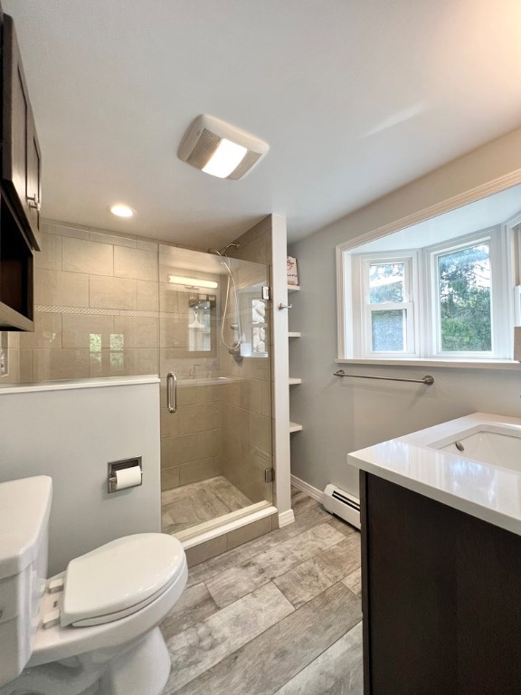 bathroom featuring vanity, a baseboard radiator, a shower with shower door, and toilet