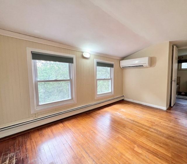 spare room featuring lofted ceiling, a baseboard heating unit, a wall mounted air conditioner, and light wood-type flooring