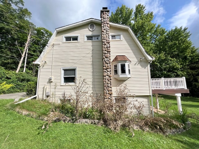 view of property exterior featuring a wooden deck and a lawn