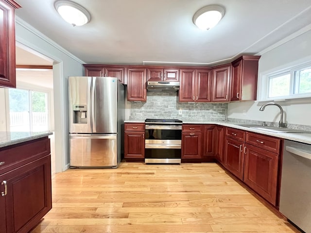 kitchen with stainless steel appliances, crown molding, sink, and light wood-type flooring