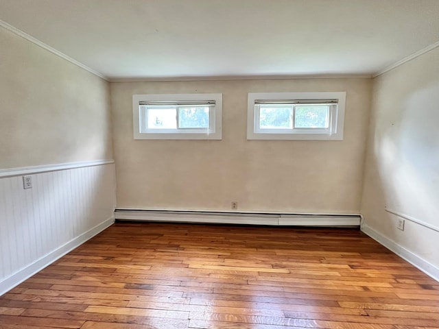 spare room with a baseboard radiator, crown molding, a wealth of natural light, and light hardwood / wood-style floors