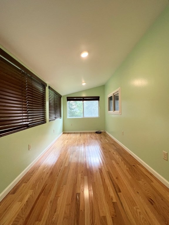 unfurnished room featuring lofted ceiling and light hardwood / wood-style floors