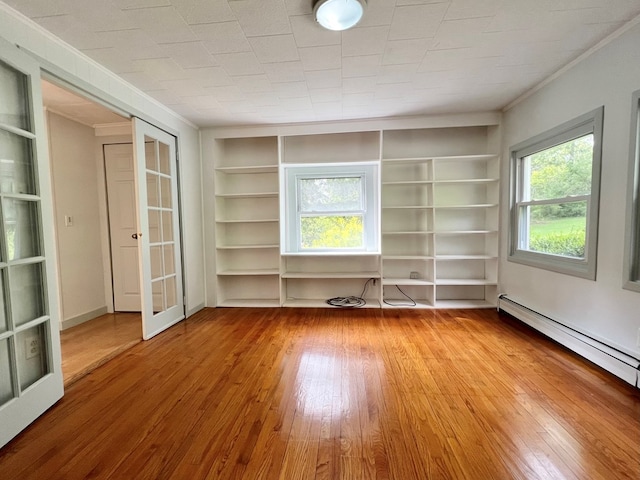 unfurnished living room with a baseboard heating unit, light hardwood / wood-style flooring, built in features, and french doors