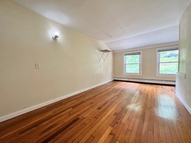 interior space with wood-type flooring, vaulted ceiling, and a baseboard heating unit