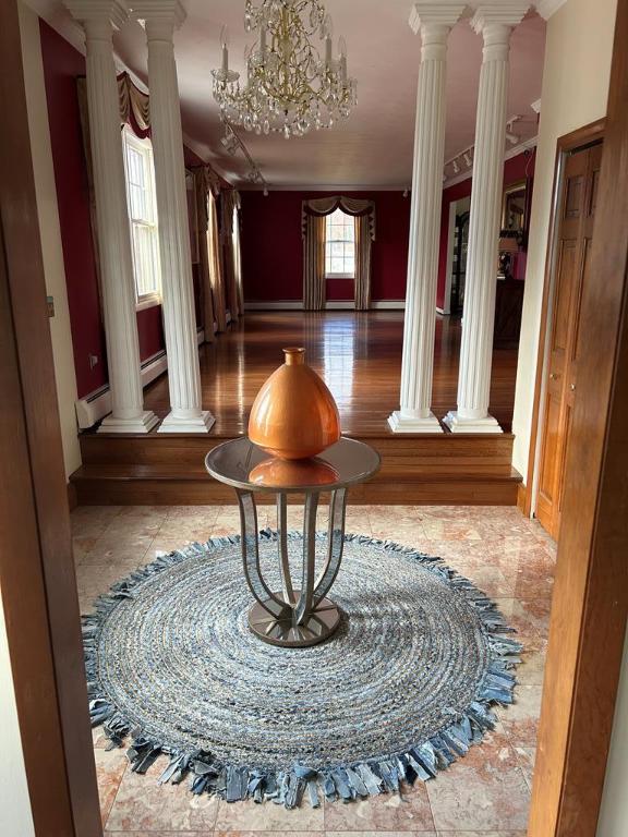 hall with a baseboard radiator, a notable chandelier, and ornate columns