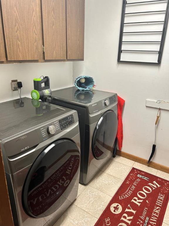 clothes washing area with cabinets, washing machine and dryer, and light tile patterned floors