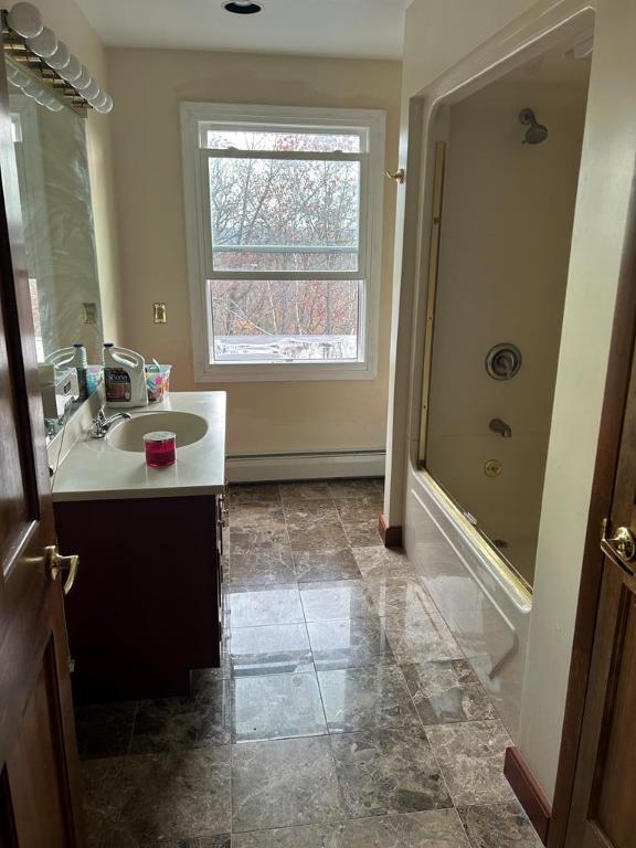 bathroom featuring vanity, shower / bath combination with glass door, and baseboard heating