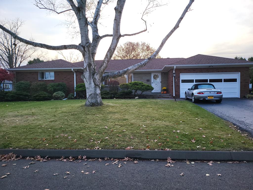 ranch-style house featuring a garage and a front lawn