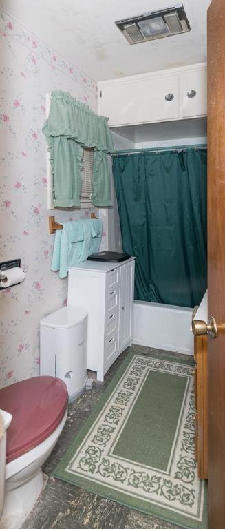 bathroom featuring toilet and shower / bath combo with shower curtain