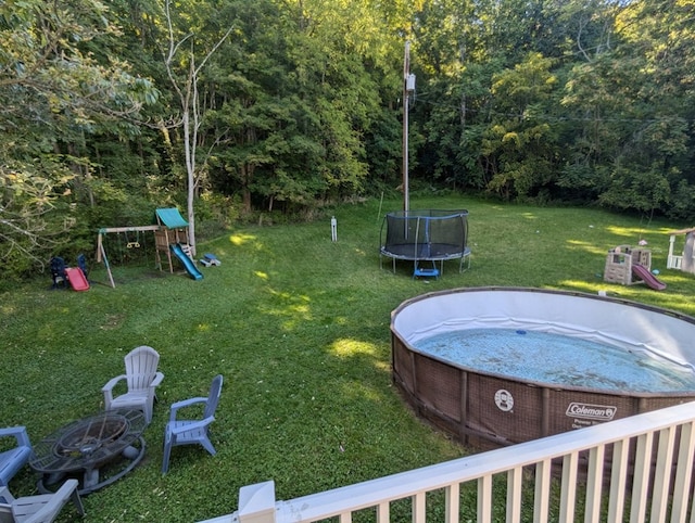 view of yard with a playground, a swimming pool, and a trampoline