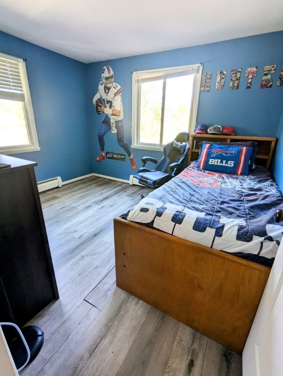 bedroom with a baseboard radiator and light hardwood / wood-style flooring