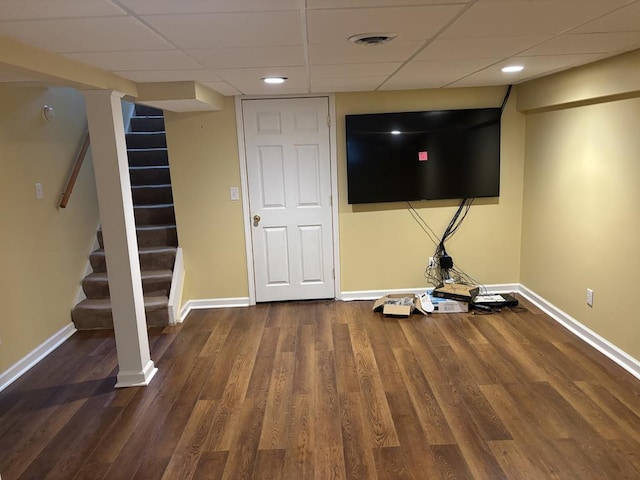 basement with a drop ceiling and dark hardwood / wood-style floors