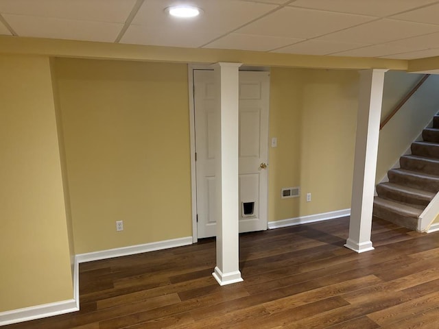 basement with a drop ceiling and dark hardwood / wood-style flooring