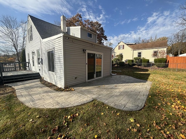 back of property featuring a wooden deck, a patio area, and a lawn