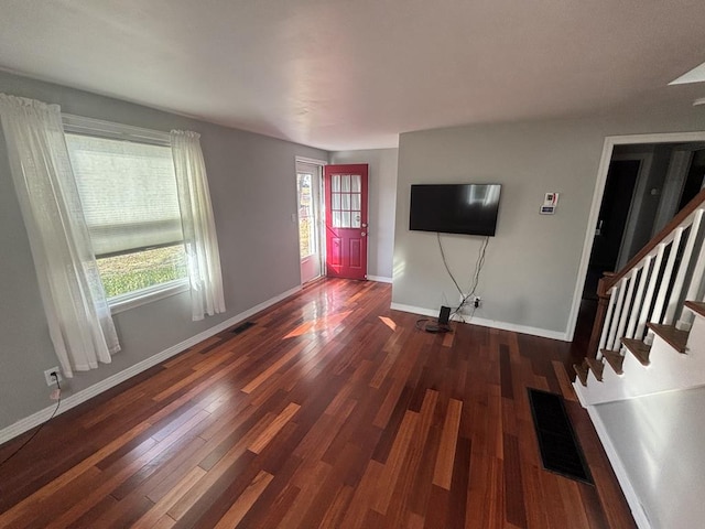 unfurnished living room featuring dark hardwood / wood-style flooring and a wealth of natural light