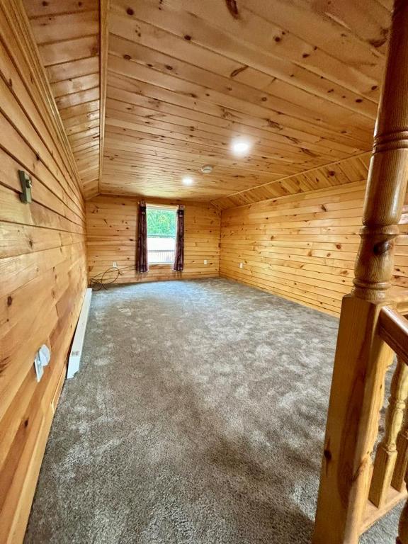 additional living space featuring carpet flooring, lofted ceiling, wooden walls, and wooden ceiling