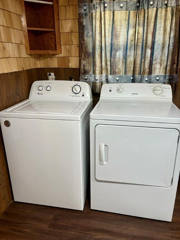 clothes washing area with separate washer and dryer, dark hardwood / wood-style floors, and wooden walls