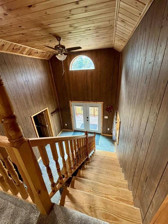 staircase featuring ceiling fan, wooden walls, high vaulted ceiling, wooden ceiling, and french doors