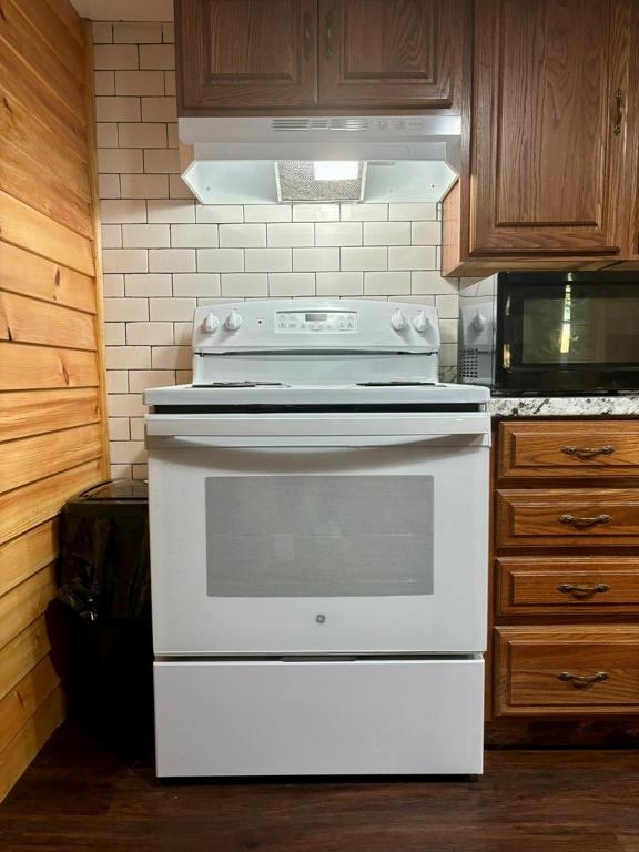 kitchen featuring exhaust hood, white range with electric stovetop, and wood walls