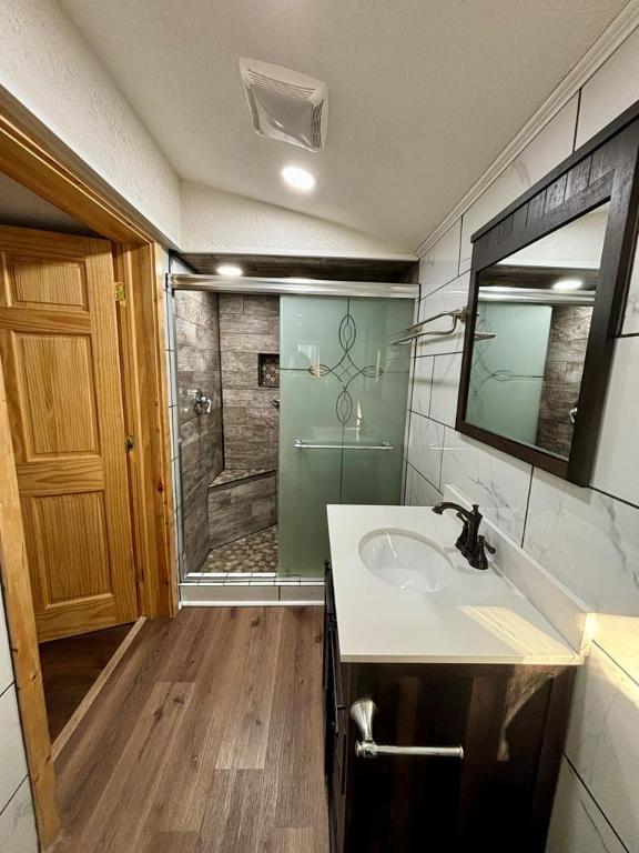 bathroom featuring lofted ceiling, tasteful backsplash, vanity, a shower with door, and hardwood / wood-style flooring