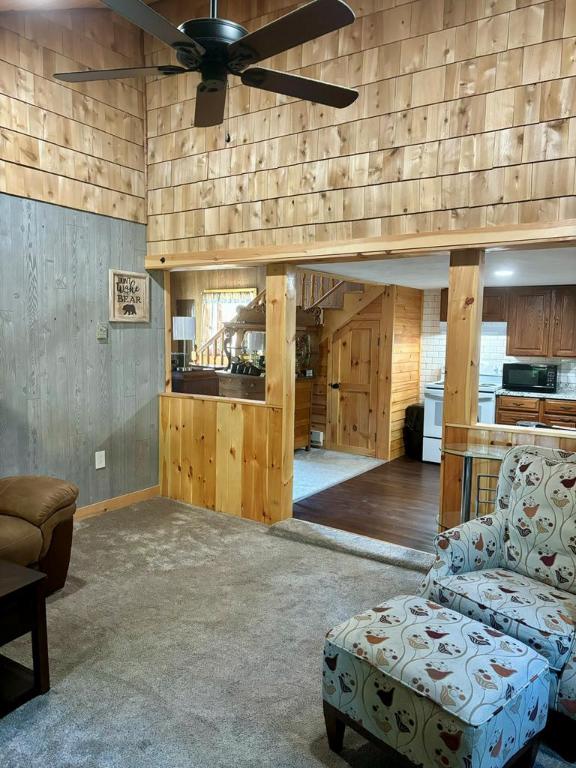 carpeted living room featuring a high ceiling, wooden walls, and ceiling fan