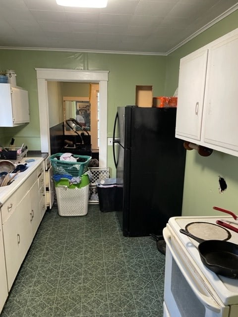 kitchen featuring white cabinetry, crown molding, white range, and black fridge