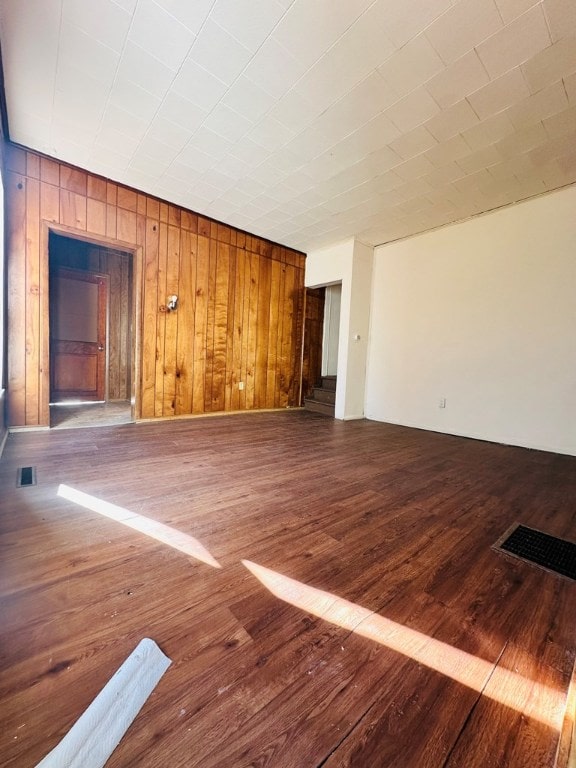 unfurnished living room with dark hardwood / wood-style flooring and wooden walls