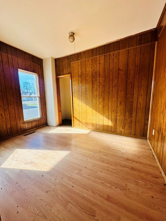 spare room with wooden walls and light wood-type flooring