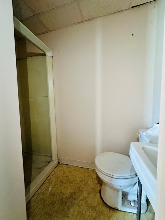 bathroom with a shower, a drop ceiling, and toilet