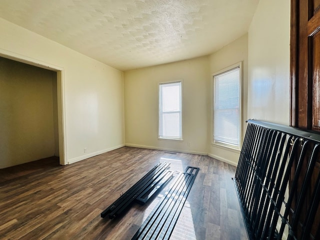 unfurnished bedroom with a textured ceiling and dark hardwood / wood-style flooring