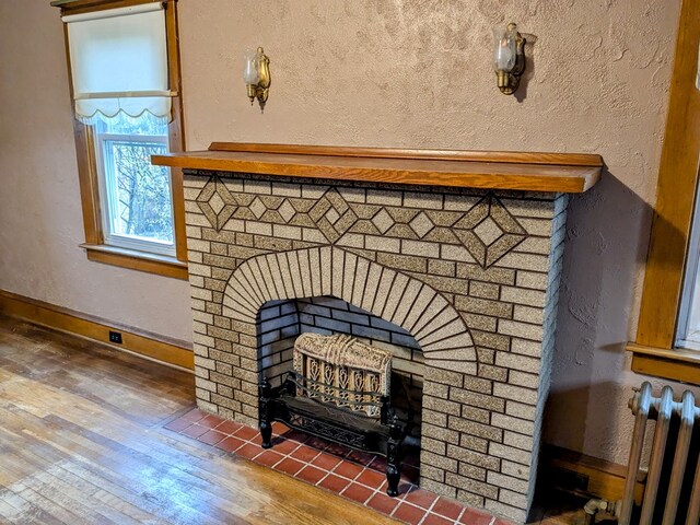 details with a brick fireplace, hardwood / wood-style flooring, and radiator heating unit