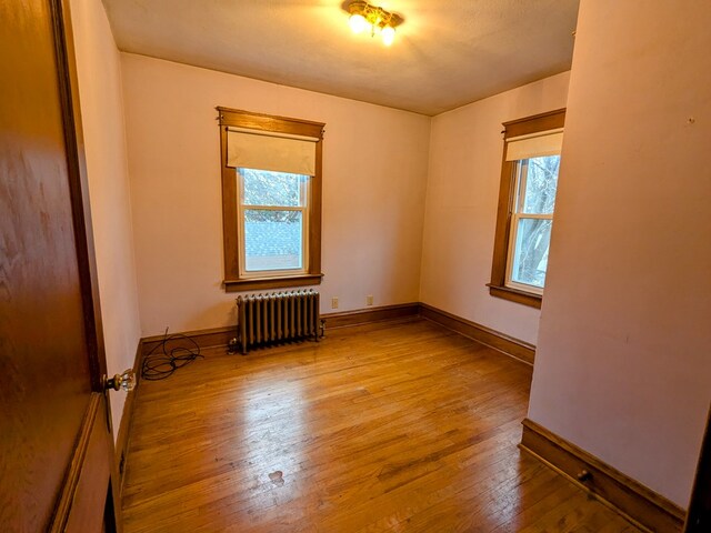 spare room featuring wood-type flooring and radiator