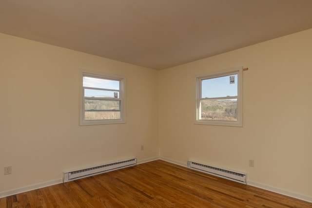 spare room with a wealth of natural light, a baseboard radiator, and hardwood / wood-style flooring