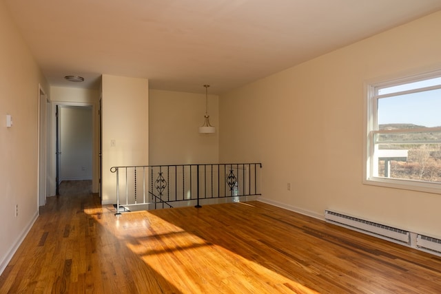 unfurnished room with baseboard heating and hardwood / wood-style floors