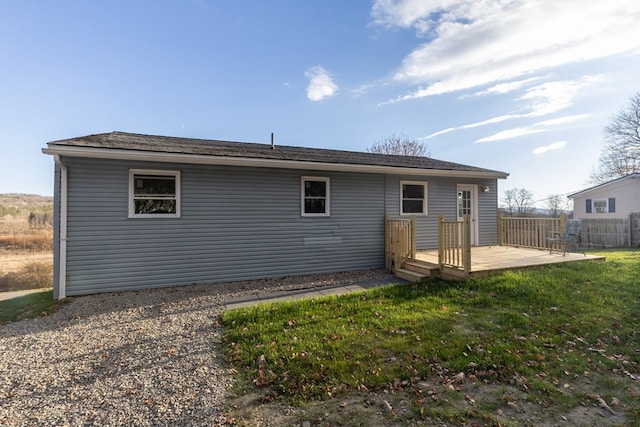 back of property featuring a deck and a lawn