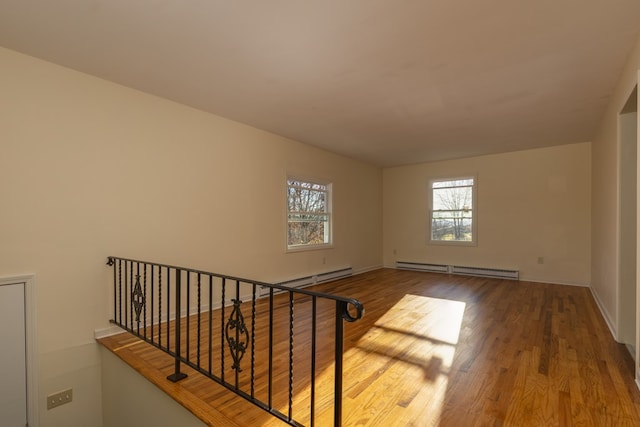 unfurnished room featuring wood-type flooring and a baseboard heating unit