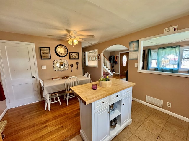 kitchen with butcher block countertops, light hardwood / wood-style flooring, white cabinets, and ceiling fan