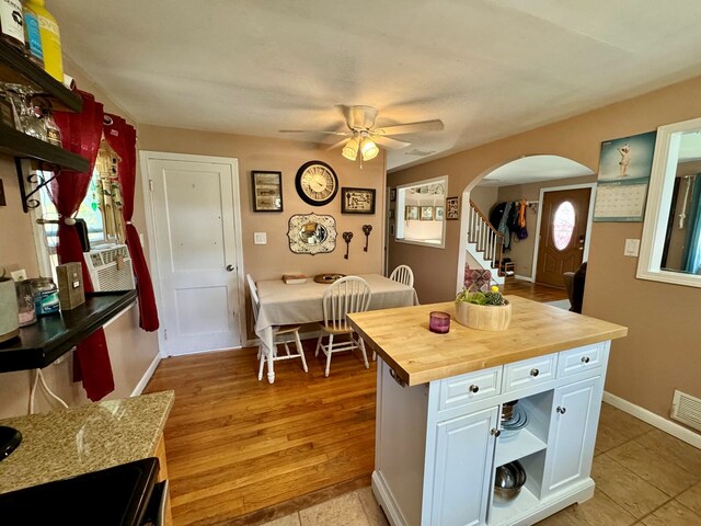 kitchen with light tile patterned flooring, butcher block counters, white cabinetry, a kitchen island, and ceiling fan