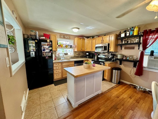 kitchen featuring sink, light hardwood / wood-style flooring, a kitchen island, stainless steel appliances, and decorative backsplash