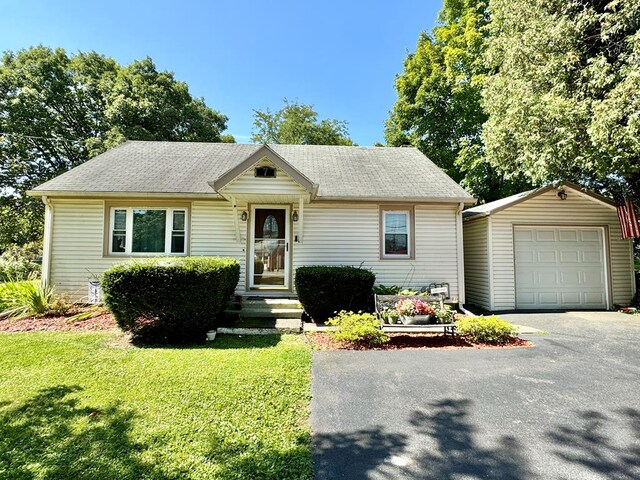 view of front of home with a garage, an outbuilding, and a front lawn