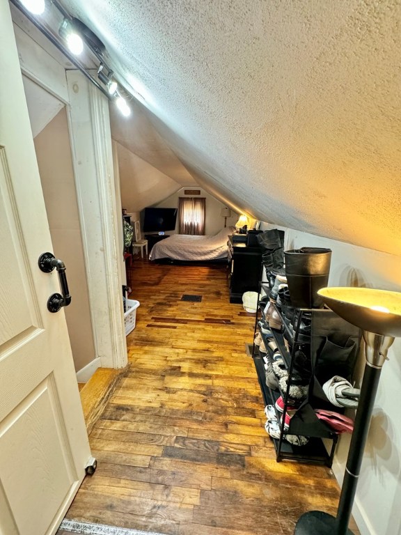 interior space with lofted ceiling, hardwood / wood-style floors, and a textured ceiling