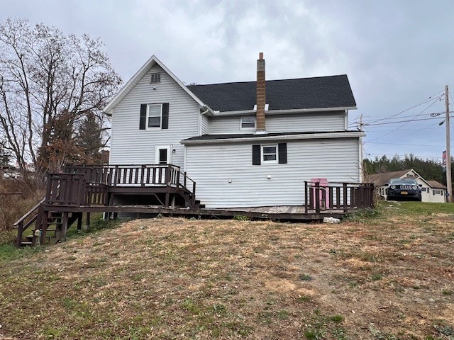 rear view of house featuring a wooden deck and a lawn