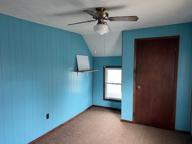 interior space with lofted ceiling, a textured ceiling, and ceiling fan