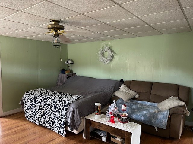 bedroom featuring ceiling fan, wood-type flooring, and a drop ceiling