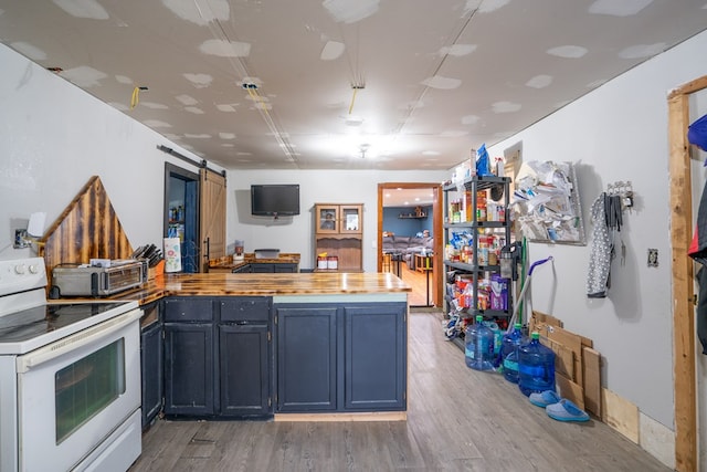 kitchen featuring a barn door, white electric range, light wood-type flooring, and kitchen peninsula